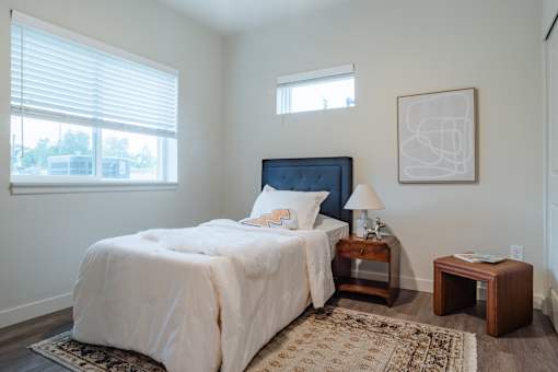 A bedroom with a large bed and a window with blinds.