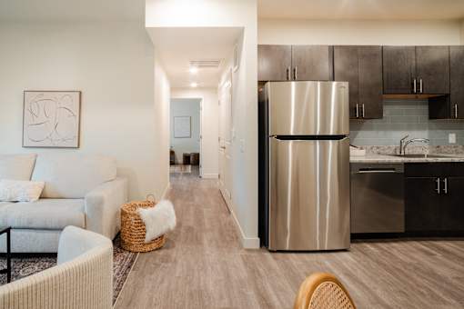 A modern kitchen with a stainless steel refrigerator and wooden flooring.