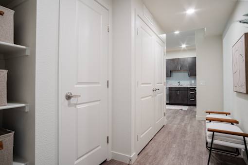 A white door is in a hallway with a bench on the right.
