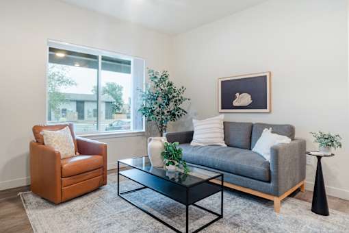 A living room with a grey couch, a brown chair, and a black coffee table.