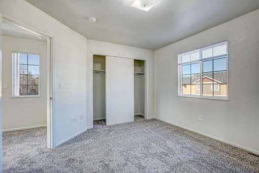 A spacious empty room with a carpeted floor and a window.