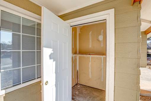 A white door is open to a room with a window and a wall.