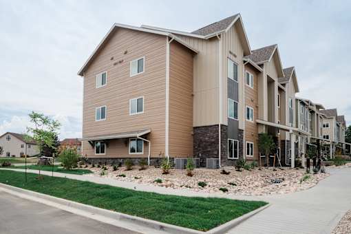 A modern apartment complex with a mix of beige and brown exterior walls.