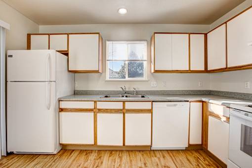 A kitchen with white appliances and wooden cabinets.