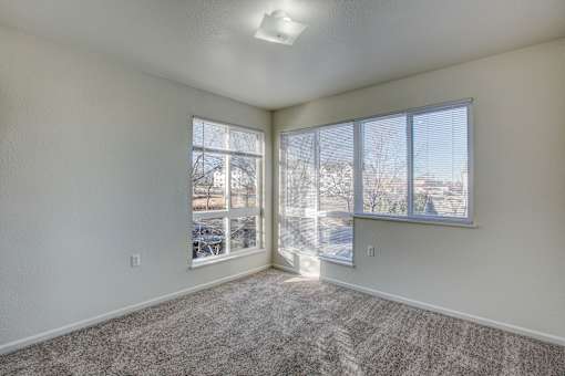 A room with a carpeted floor and a window with blinds.