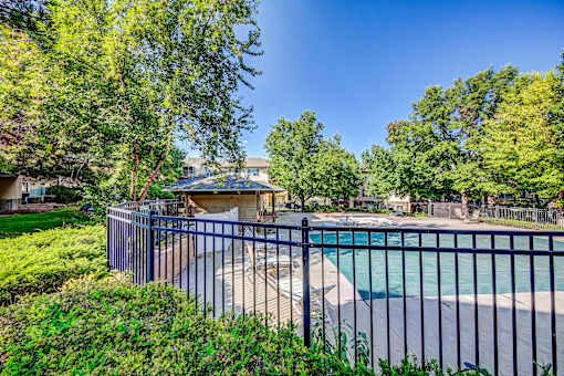 a fenced in swimming pool with a gazebo and trees