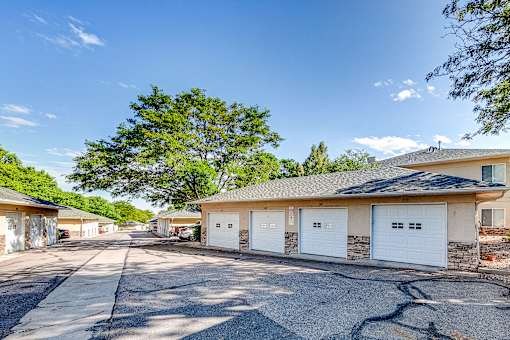 the driveway of a house with white garage doors and a tree