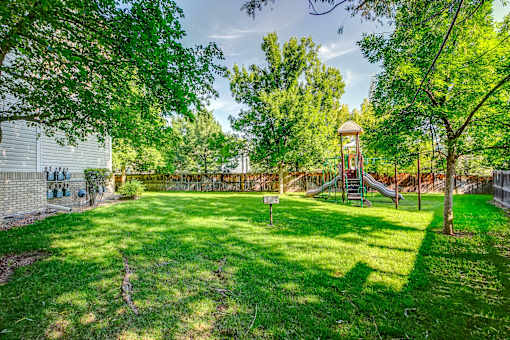 a backyard with a swing set and a green lawn