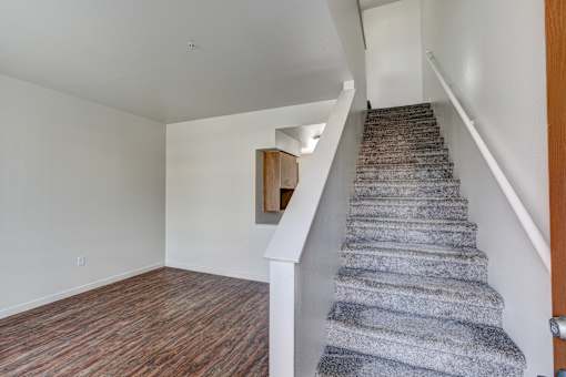 an empty living room with a staircase in a home with wood flooring