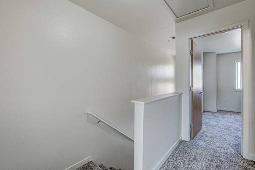 an empty room with a hallway and a door to a bedroom
