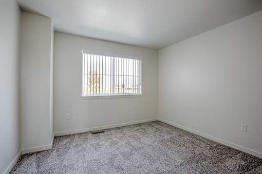 a spacious living room with carpet and a window