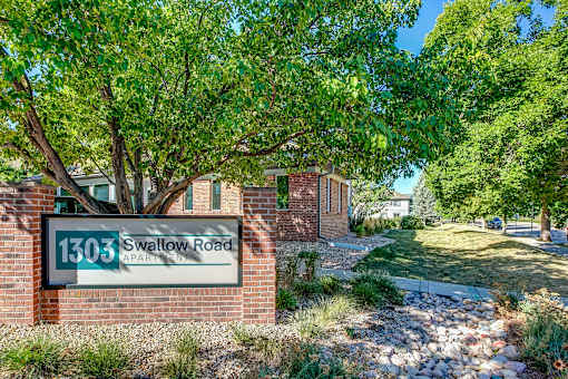 a sign in front of a brick building with a tree