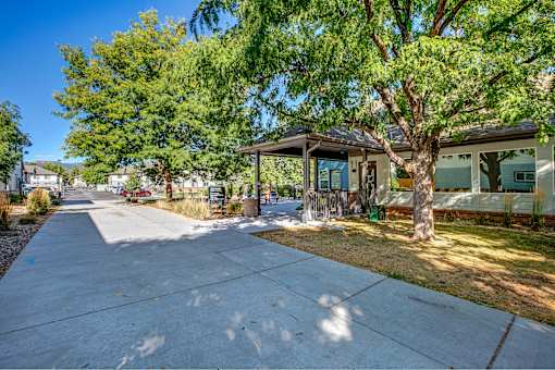 a sidewalk in front of a house with trees