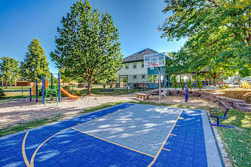 a basketball court with trees and a building in the background
