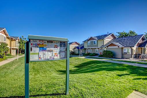 a sign in the grass in front of some houses