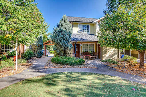 the front yard of a house with a driveway and trees