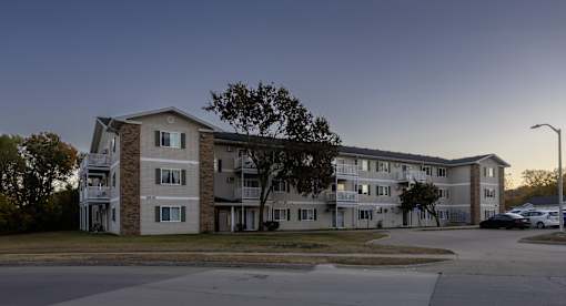 an apartment building on a street corner at dusk