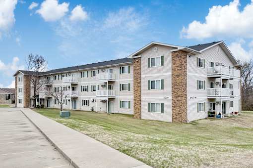 Apartment building with a parking lot in front.