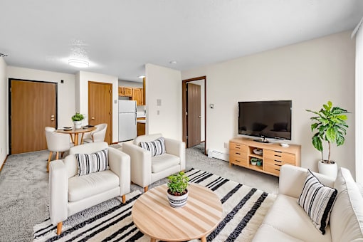 A living room with a white couch, a wooden coffee table, and a television.