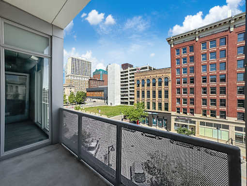 A balcony with a mesh screen overlooking a cityscape.
