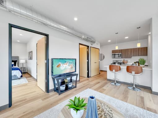 a living room with a tv and a kitchen with a bar