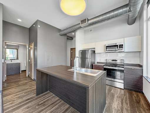 A modern kitchen with a wooden island and stainless steel appliances.
