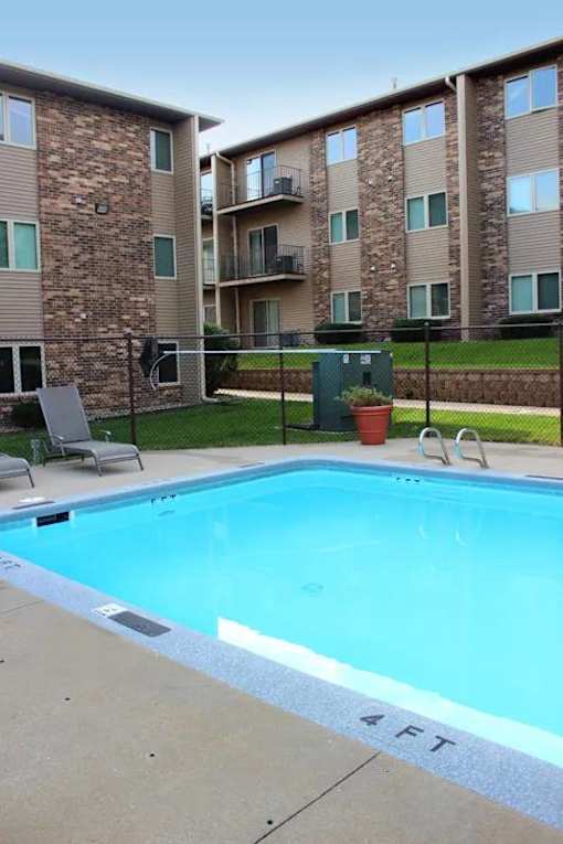 A swimming pool in front of a brick apartment building.