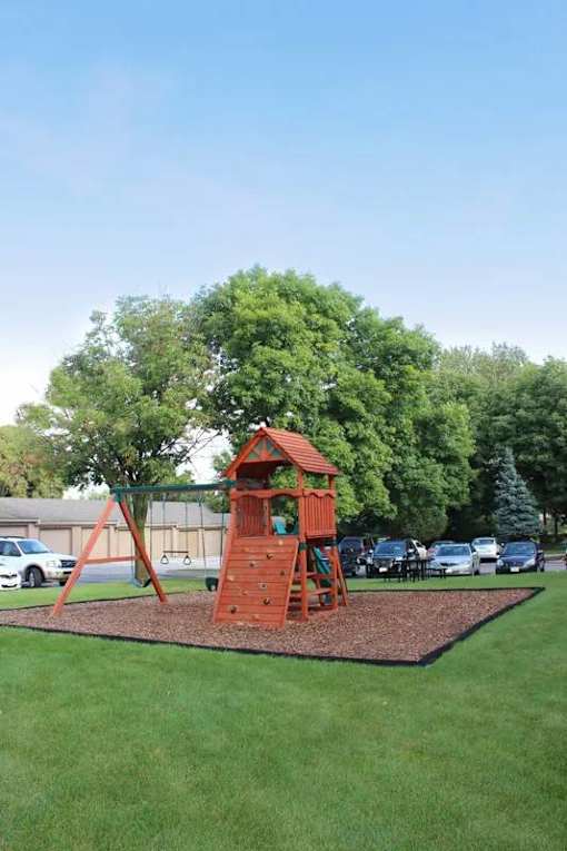 A playground with a red swing set and a tree.