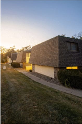 A modern house with a dark roof and bright windows is shown.
