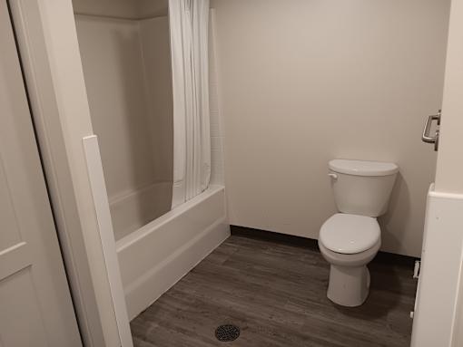A white toilet in a small bathroom with a white shower curtain.
