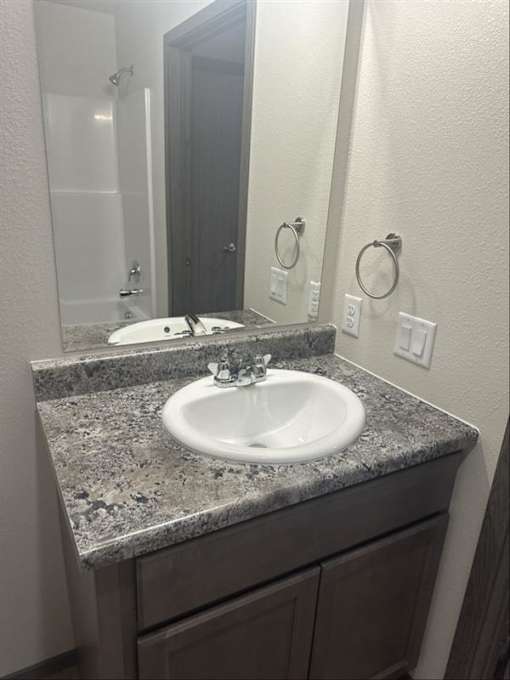 A bathroom sink with a granite counter top.