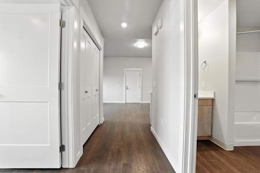 A hallway with white doors and wood floors.