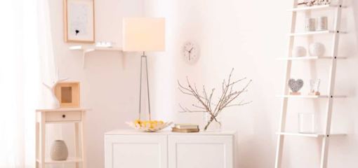 A white shelf with decorative items sits on a wall.