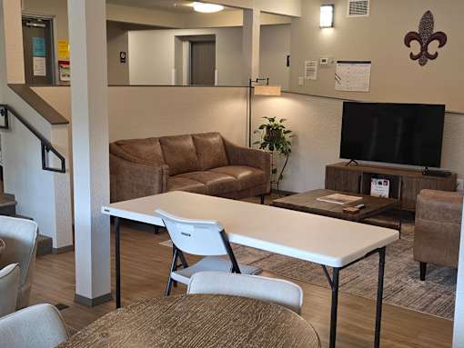 A community room with a white table and brown chairs.
