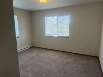 A room with a carpeted floor and a window with blinds.