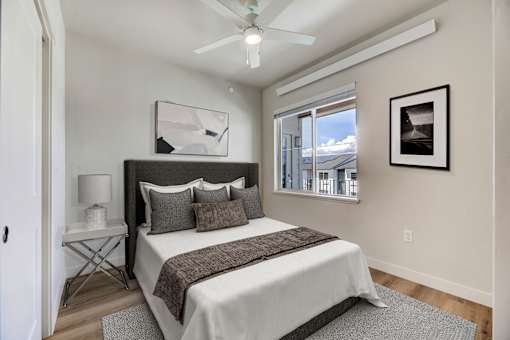 A bedroom with a bed, a ceiling fan, and a window overlooking a snowy landscape.