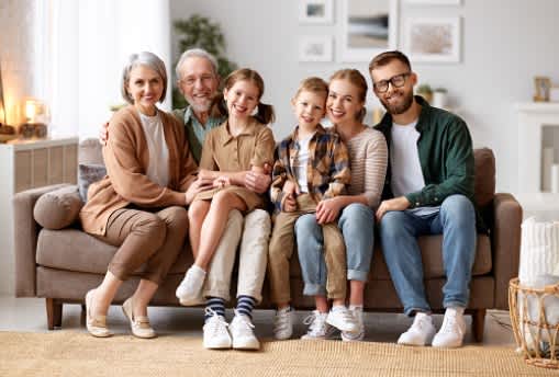 A family of five is sitting together on a couch in a living room.