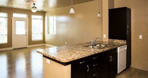 kitchen with a granite counter top looking into living room showing large windows