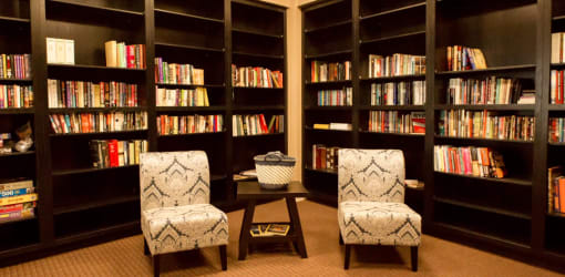 a library with two chairs and two bookshelves