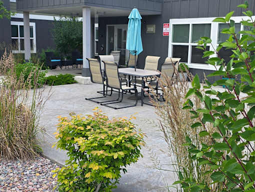 A patio with a table and chairs and a blue umbrella.