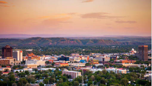 A cityscape of Billings Montana  with buildings and trees under a sunset sky.