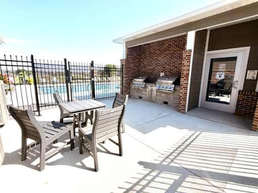 A patio with a table and chairs and a pool in the background.