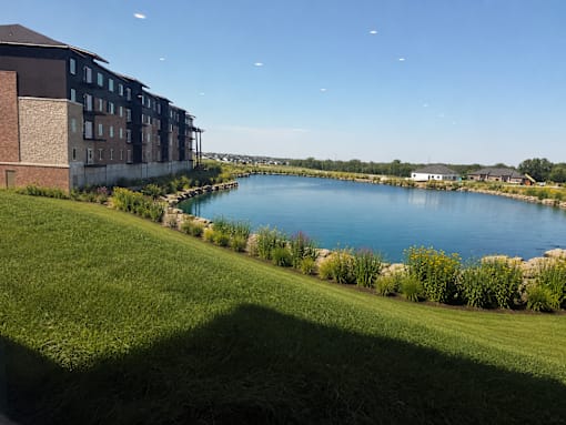 A large body of water surrounded by grass and buildings.