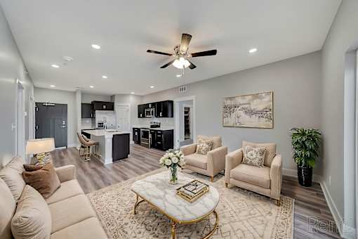 A living room with a beige sofa, a coffee table, and a ceiling fan.