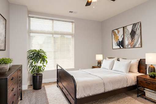 A bedroom with a bed, dresser, and ceiling fan.