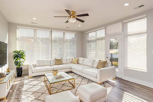 A white living room with a glass coffee table and a white sofa.