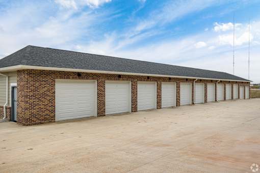 A long building with a grey roof and white garage doors.
