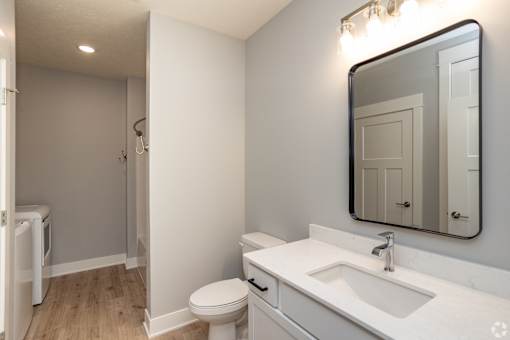 A white bathroom with a toilet, sink, and mirror.