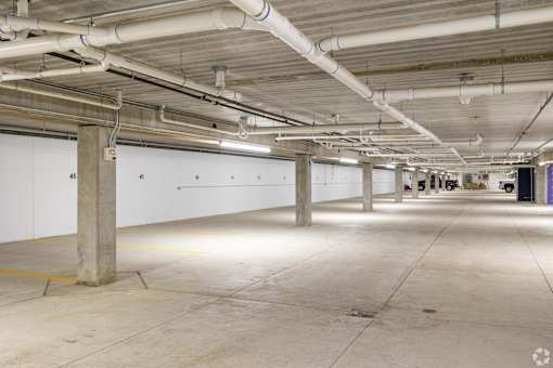 A large, empty parking garage with concrete floors and white walls.