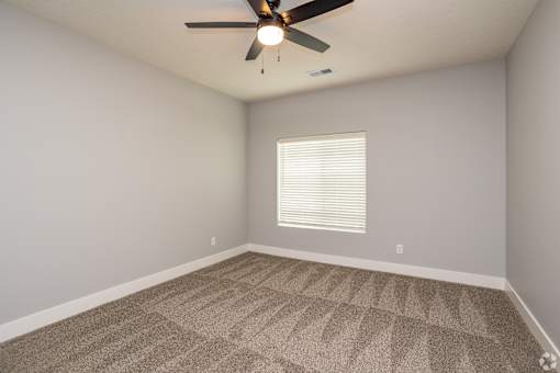 A room with a ceiling fan and carpeted floor.